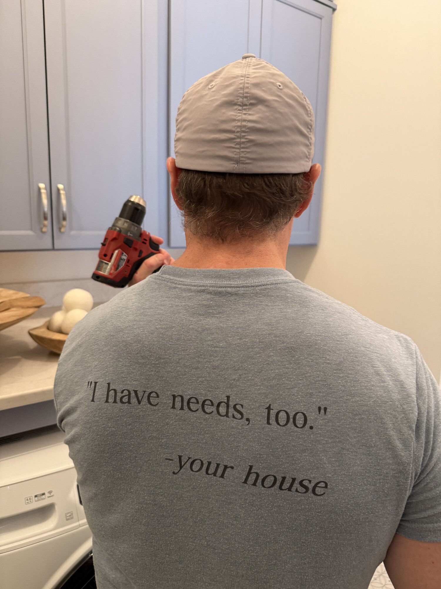 Haven team member in a "I have needs, too. —your house" t-shirt installing hardware in a client kitchen
